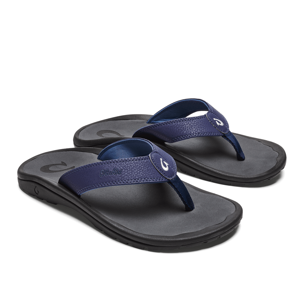 OluKai Ohana sandals in dark blue with textured straps and embroidered logo, cushioned footbed, and black outsole, angled front view.