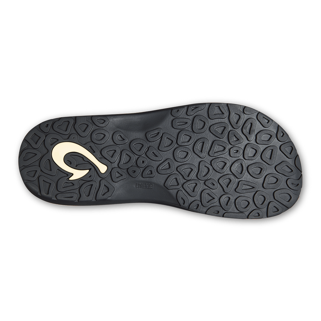 OluKai Ohana sandal outsole in black rubber with textured traction pattern and embossed logo, bottom view.