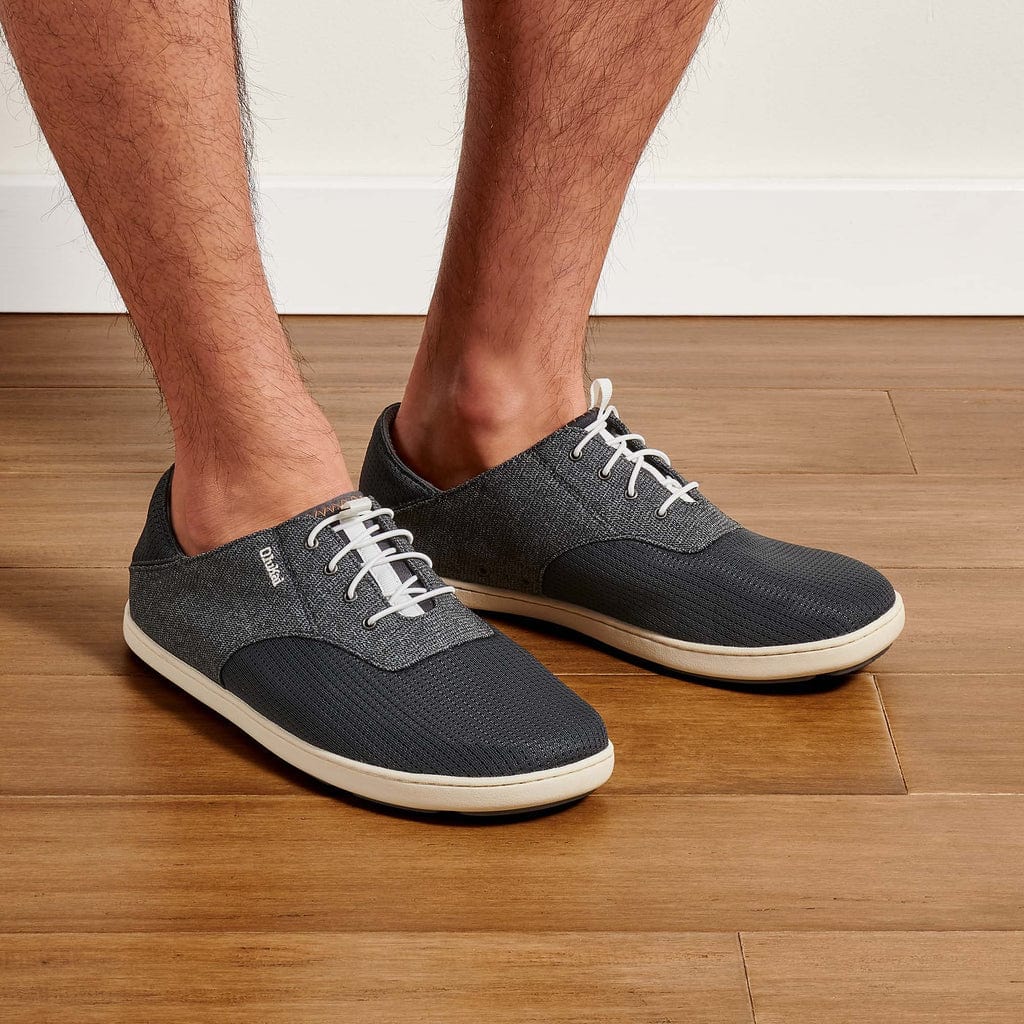 OluKai Nohea Moku casual shoes in dark gray with breathable mesh upper, lightweight design, and white laces, lifestyle view.