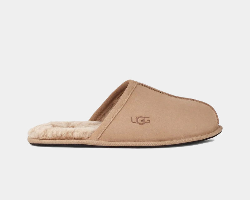 A light tan UGG Scuff slipper with a suede upper and sheepskin lining, featuring the UGG logo embossed on the outsole.