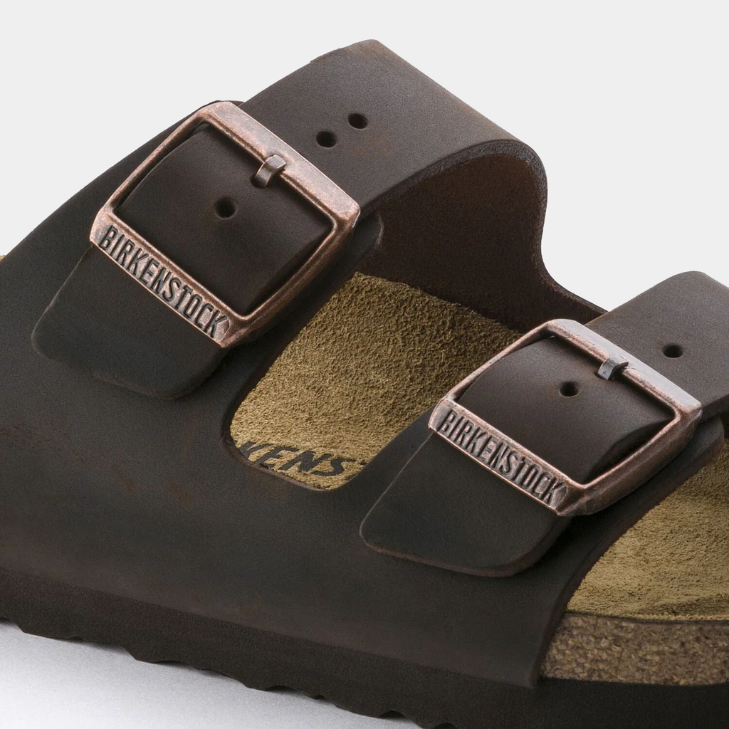 Birkenstock Arizona Oiled Leather sandals in dark brown with dual adjustable straps and copper-tone buckles, close-up side view.