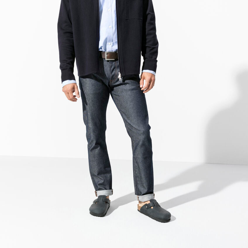 Birkenstock Boston Oiled Leather clogs in dark gray with adjustable strap and cork sole, worn by man standing.