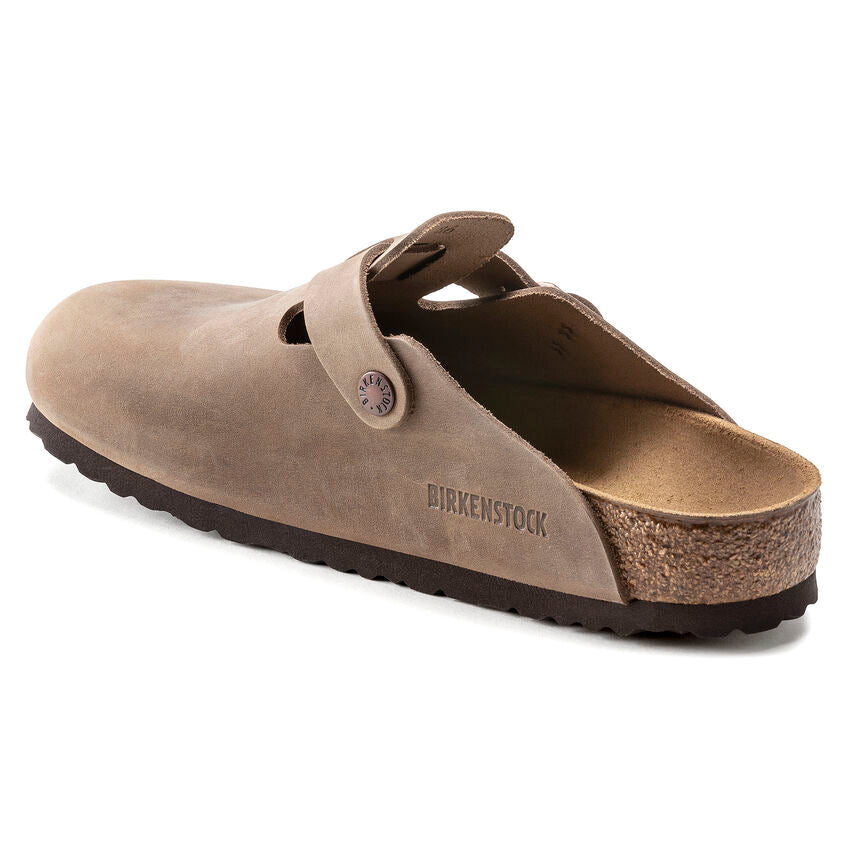 Birkenstock Boston Oiled Leather clogs in taupe with adjustable strap and cork footbed, back angle view.