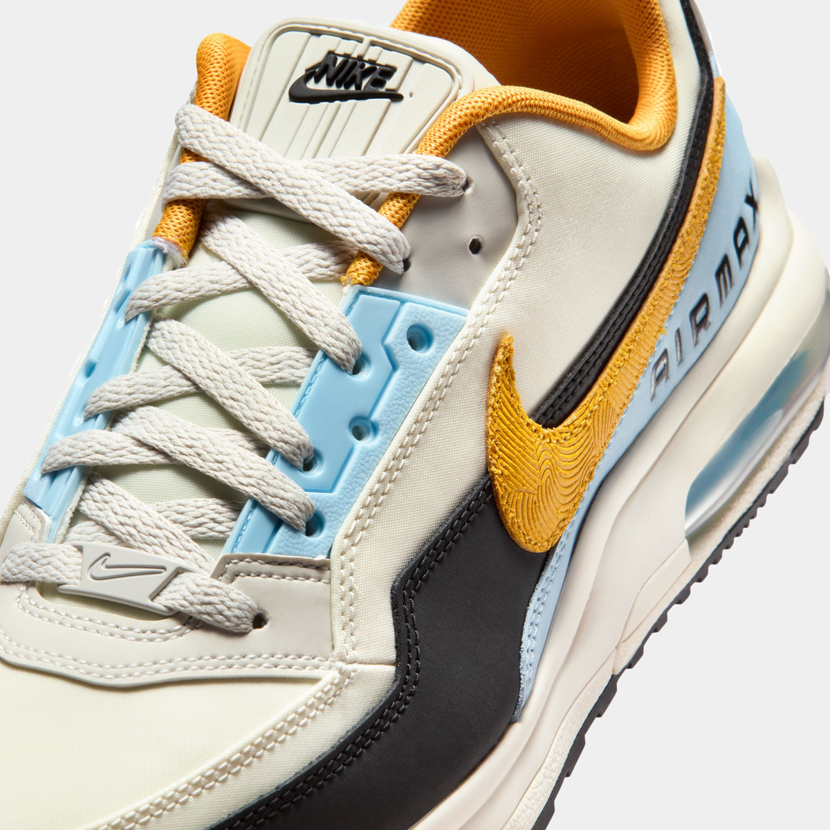 Close-up of a Nike sneaker with beige, yellow, and black design elements on a white background