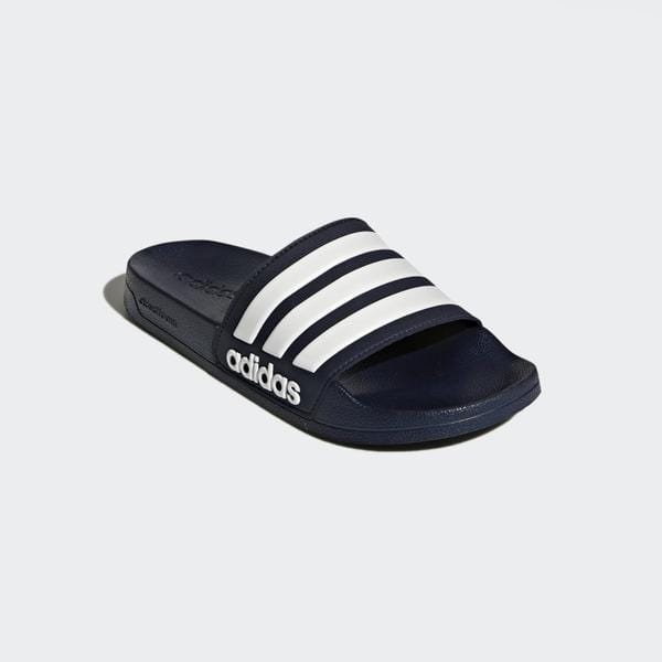 Adidas Adilette Shower Slides in navy blue with white stripe design, cushioned footbed, and branded logo, angled side view.