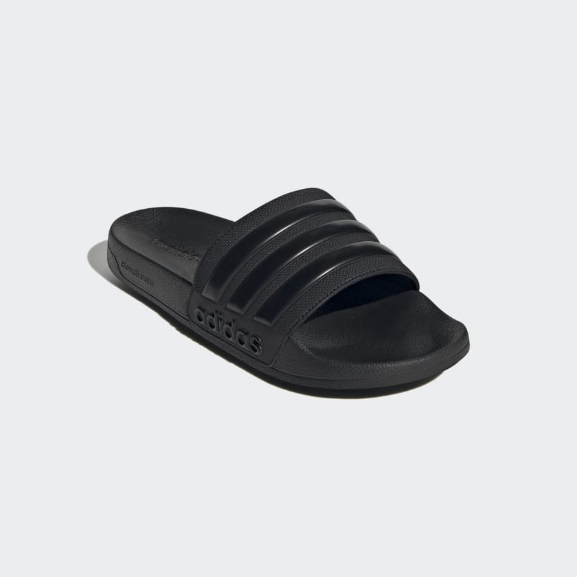 Adidas Adilette Shower Slides in black with textured strap and molded footbed, angled front view.