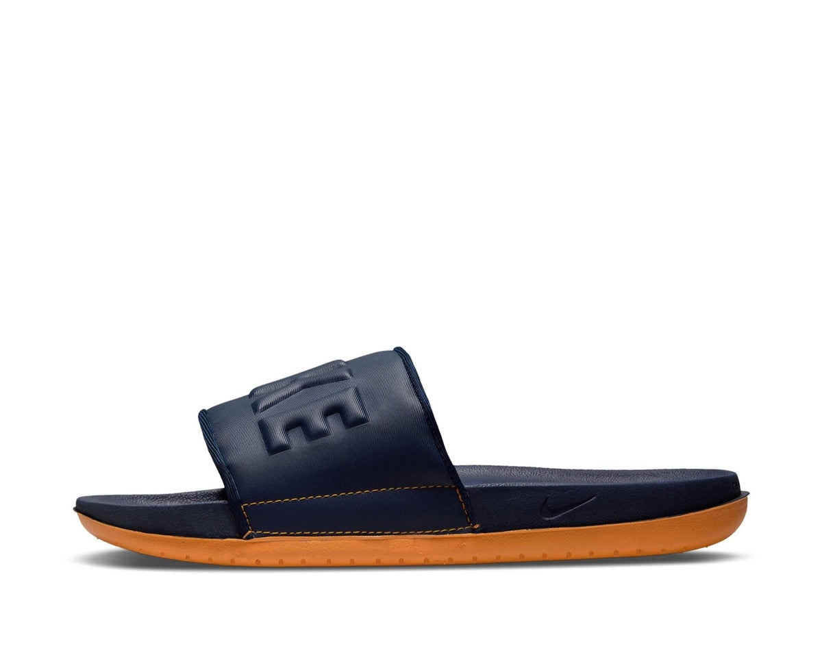 Nike Offcourt Slide sandals in navy blue with an embossed strap and cushioned orange sole, side view.