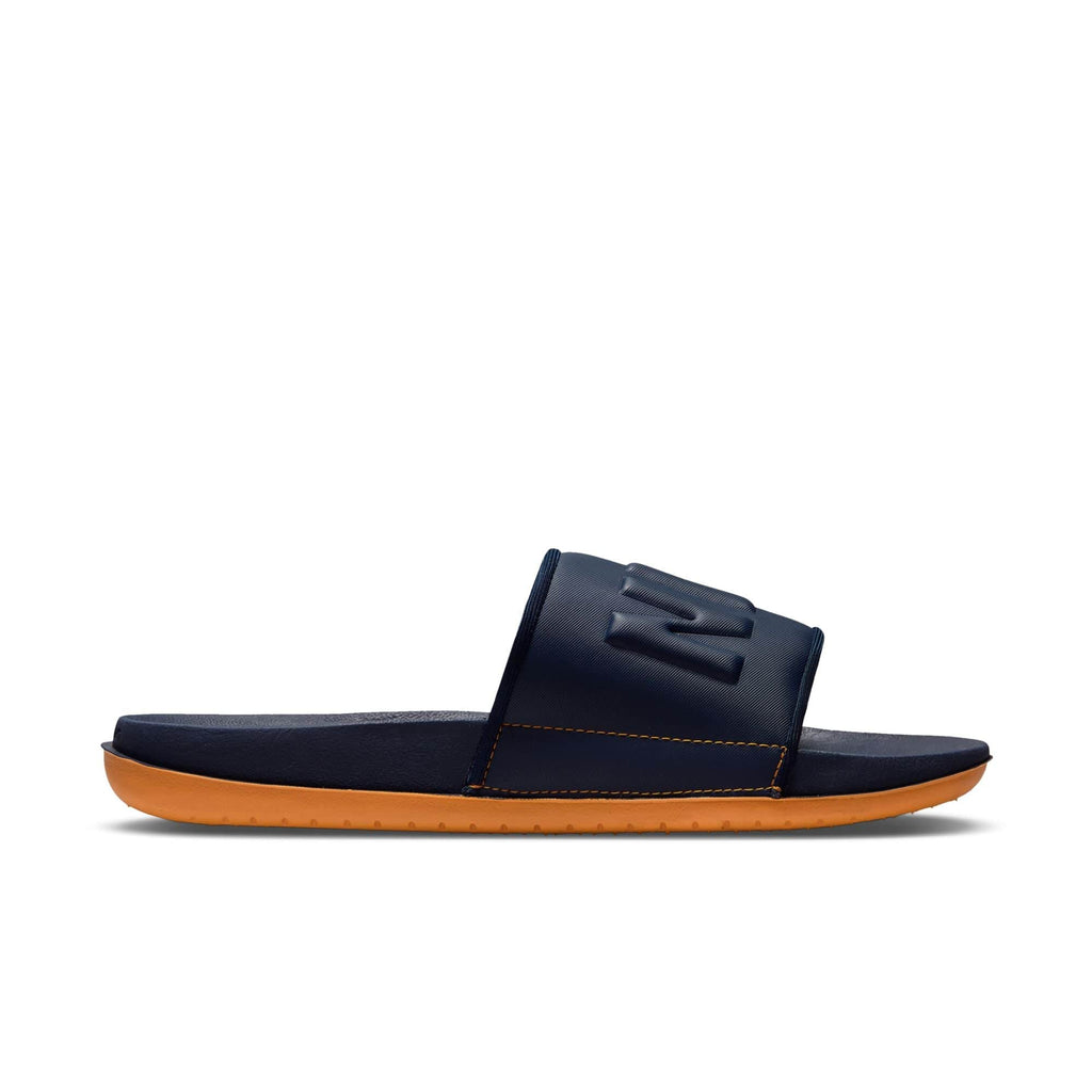 Nike Offcourt Slide sandals in navy blue with an embossed logo on the strap and orange foam sole, side view.