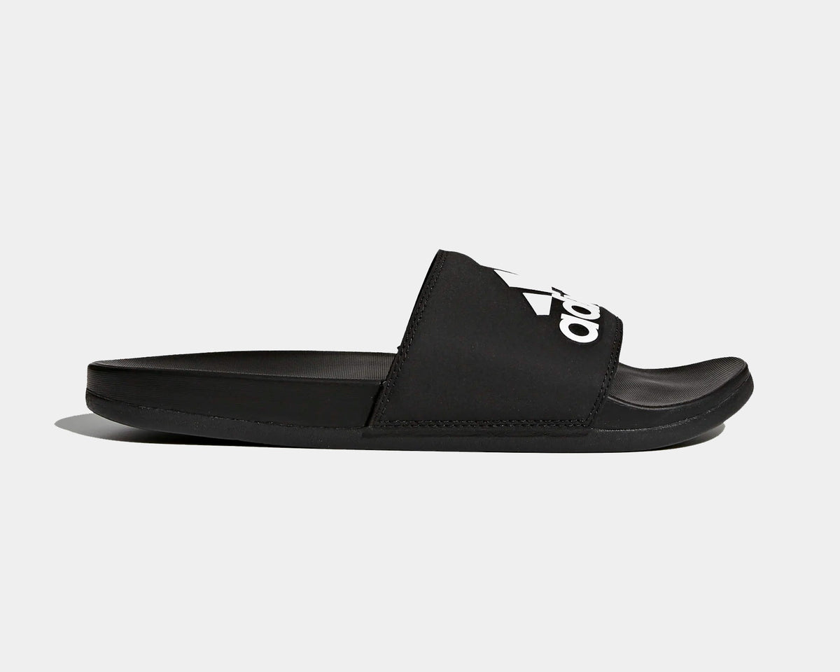 Adidas Adilette Comfort Slides in black with logo-adorned synthetic strap and cushioned footbed, side view.