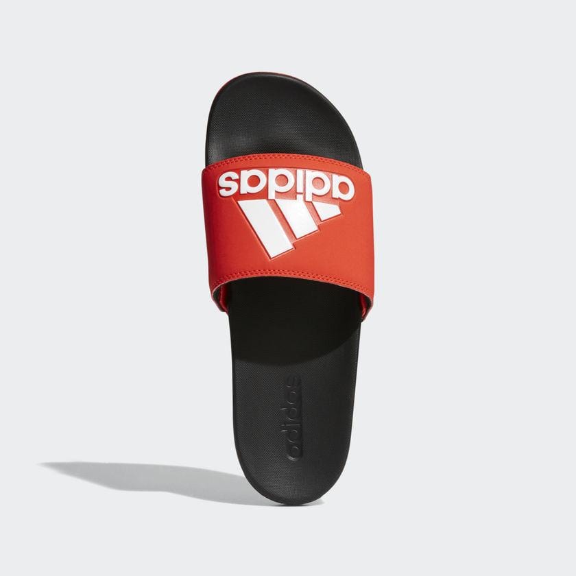 Adidas Adilette Comfort Slides in red with bold white logo on soft strap and black contoured footbed, top view.