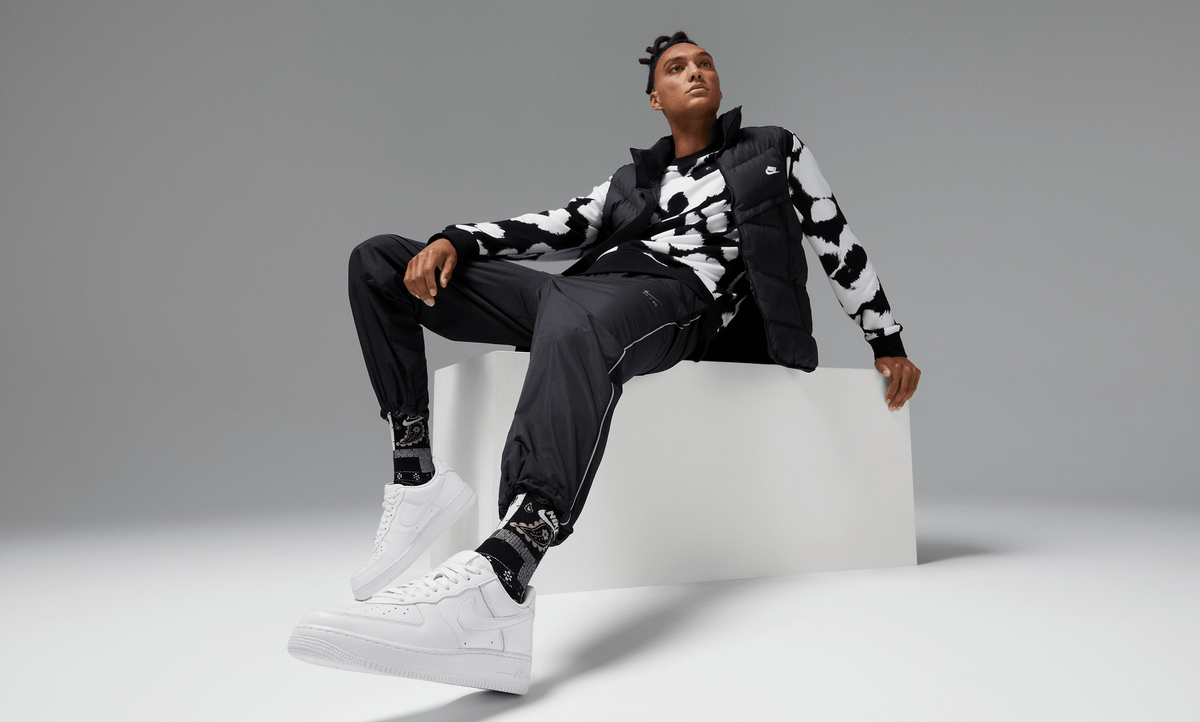 Nike Air Force 1 '07 sneakers in clean white leather design with perforated toe box and signature Swoosh logo, lifestyle setting.