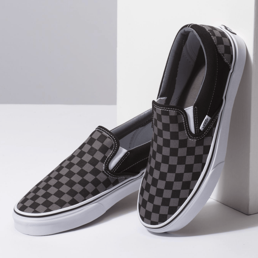Vans Checkerboard Slip On shoes in black and gray checkered canvas with white soles, angled front and side view.