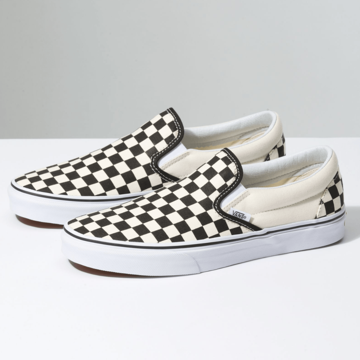 Vans Checkerboard Slip On shoes with black and white canvas upper, padded collar, and white rubber outsole, side angle view.
