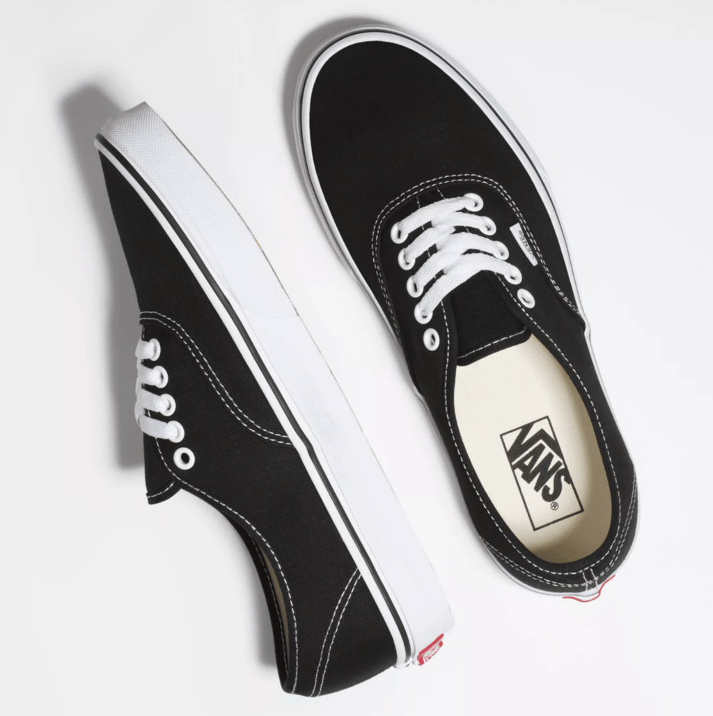 Vans Authentic sneakers in black canvas with white stitching, laces, and rubber outsole, top angled view.
