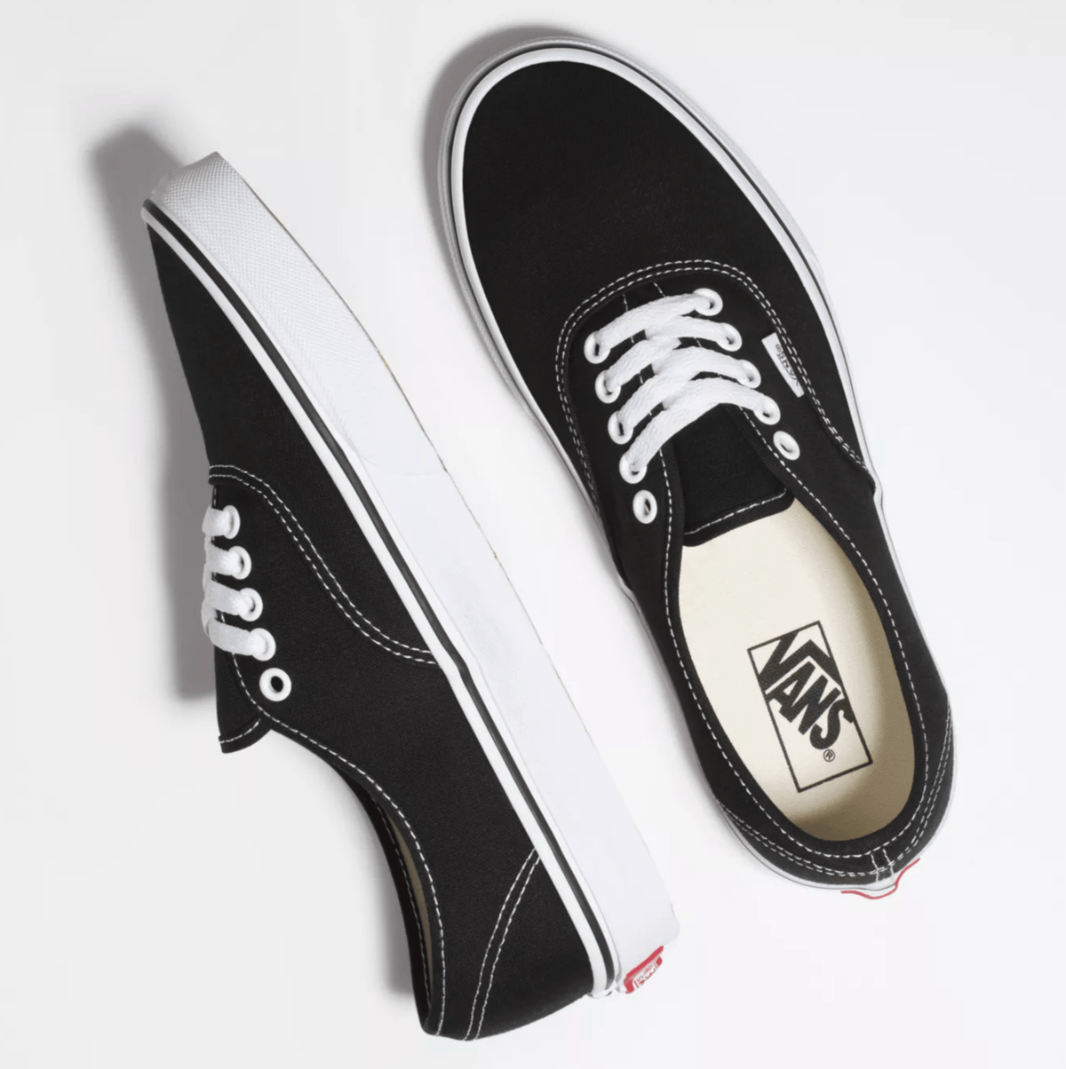 Vans Authentic sneakers in black canvas with white stitching, laces, and rubber outsole, top angled view.