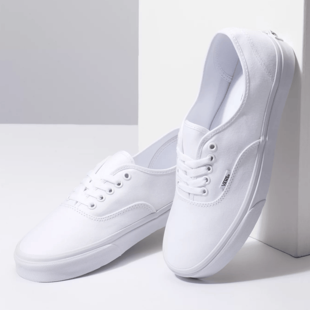 Vans Authentic shoes in white canvas with lace-up closure and vulcanized rubber outsole, angled side view.