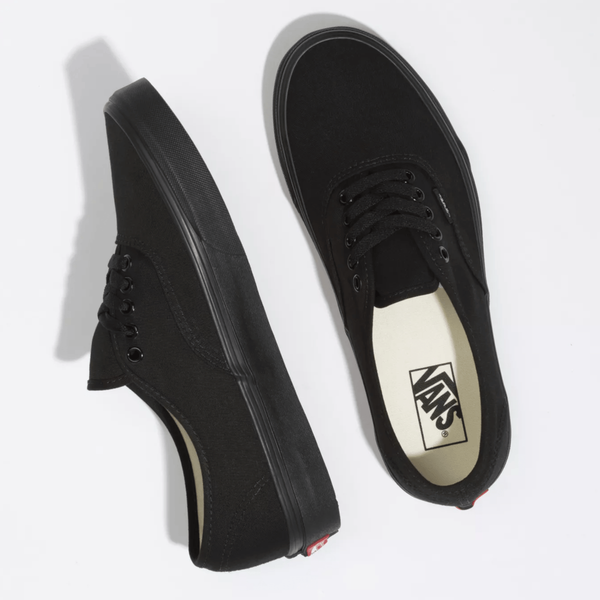 Vans Authentic sneakers in all-black with canvas upper, metal eyelets, and vulcanized rubber sole, top view.