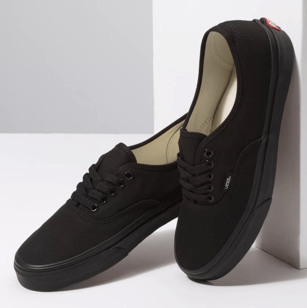 Vans Authentic sneakers in black with canvas upper, lace-up closure, and rubber outsole, angled side view.