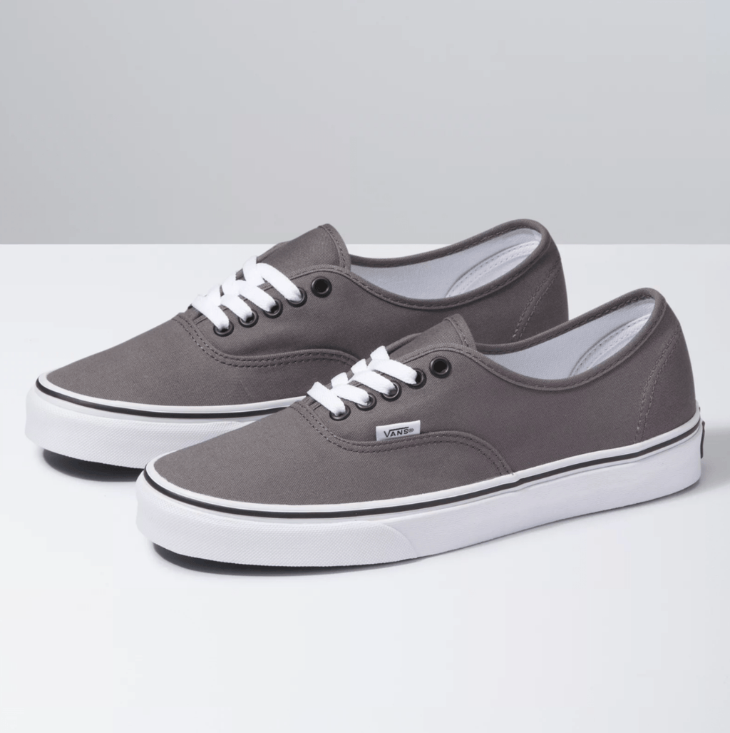 Vans Authentic sneakers in gray with canvas upper, white laces, metal eyelets, and vulcanized rubber outsole, angled side view.