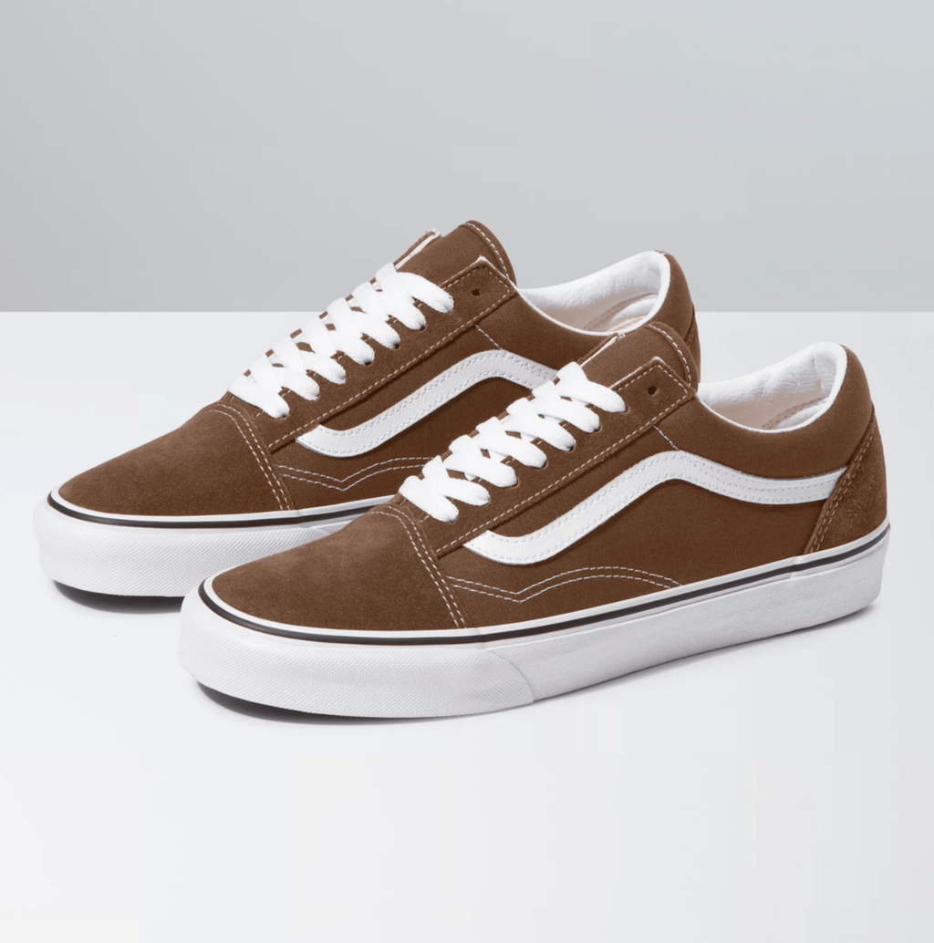 Vans Old Skool sneakers in brown suede with white leather side stripe, white laces, and a rubber waffle outsole, side/front angle.