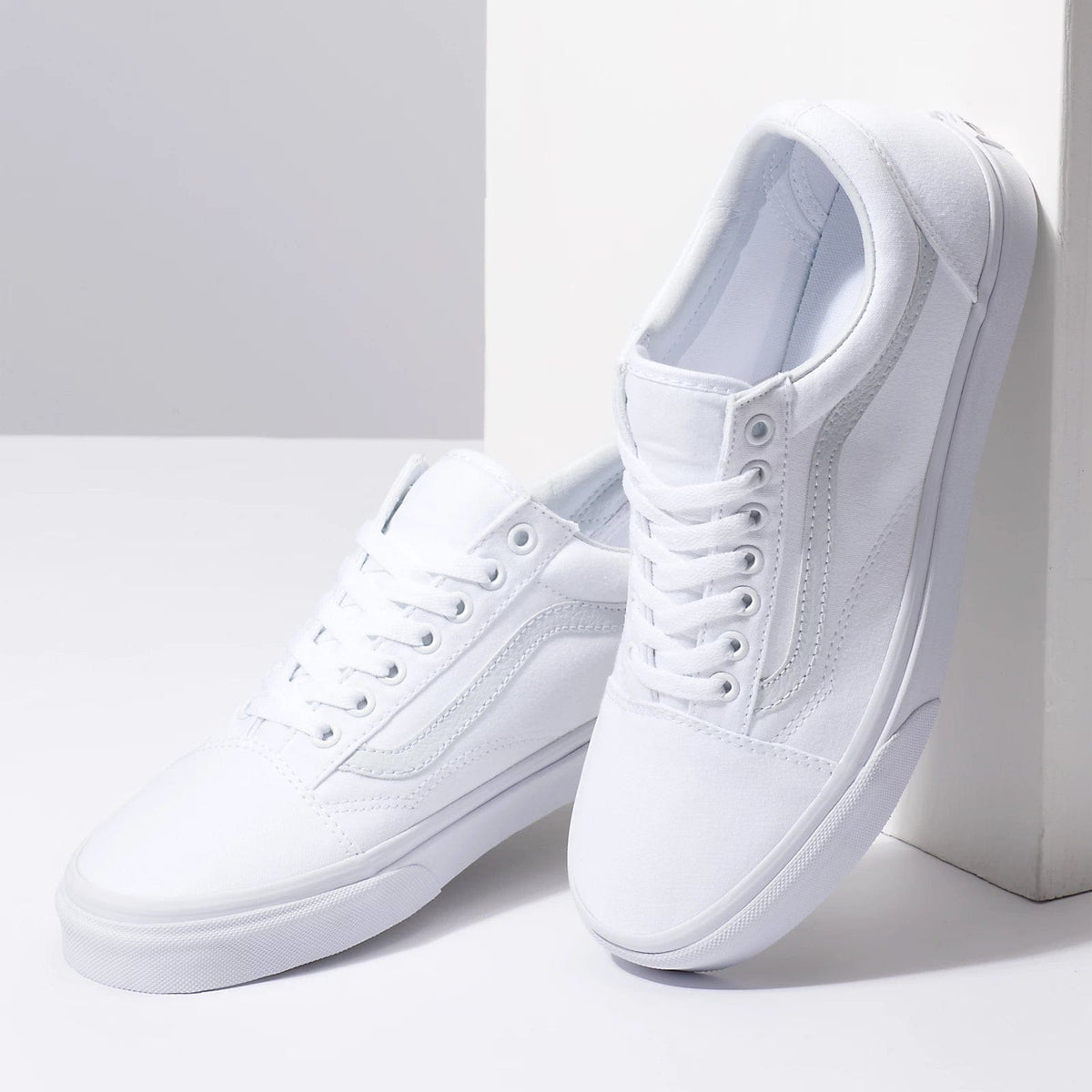 Vans Classic Old Skool sneakers in white with canvas upper, suede details, and signature side stripe, angled side view.