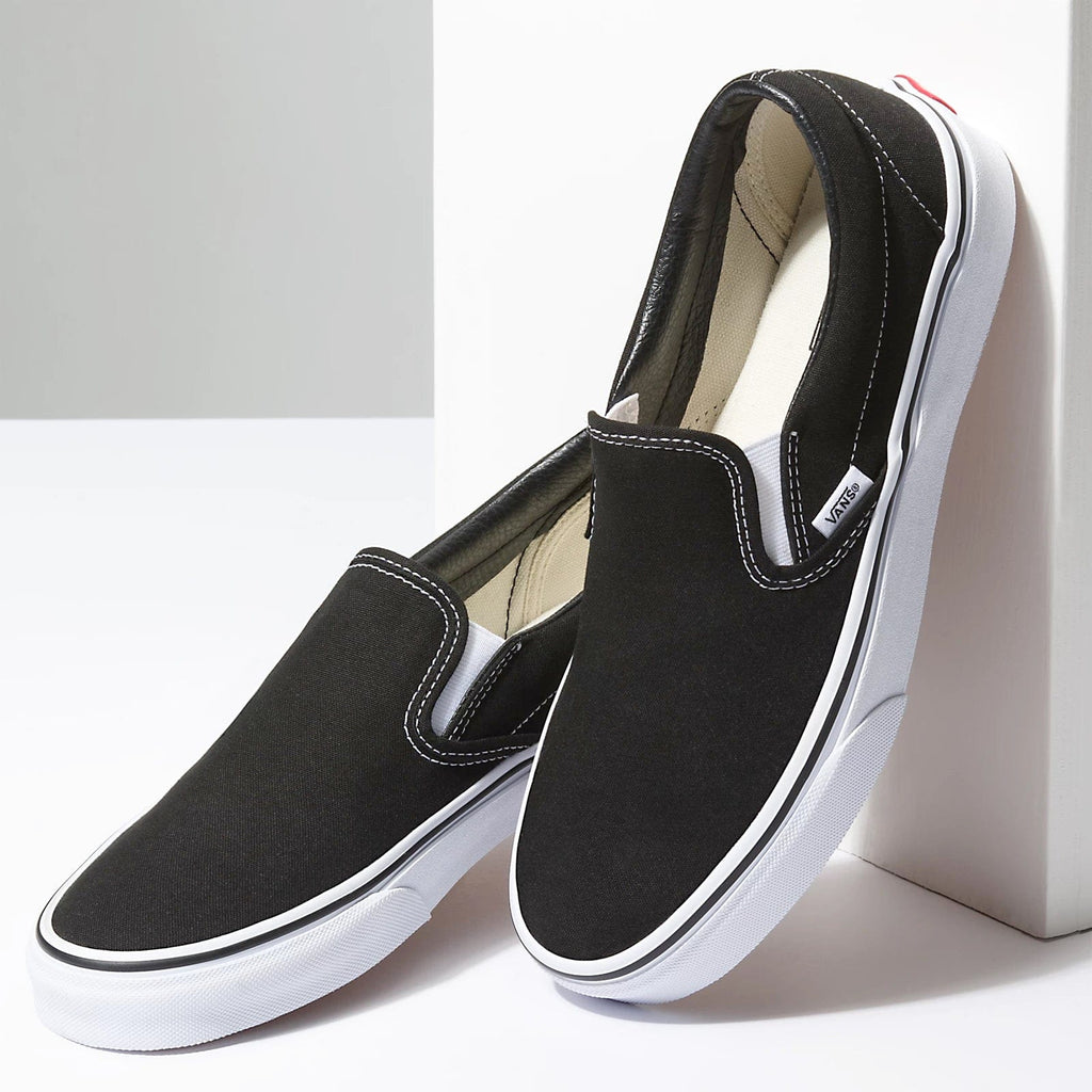 Vans Classic Slip On shoes in black canvas with white stitching and rubber soles, side angle showcasing casual design.