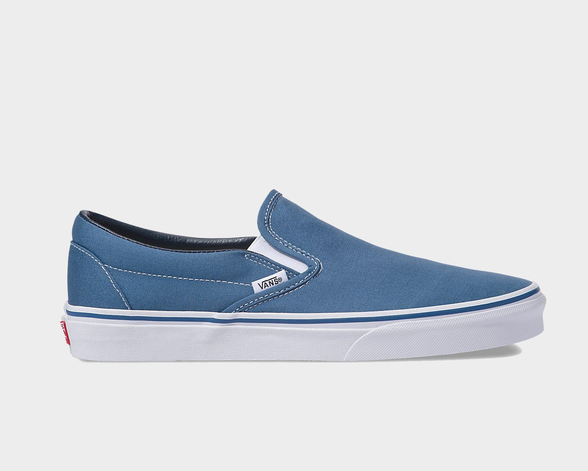 Vans Classic Slip On sneakers in blue canvas with white stitching and rubber midsole, side view.