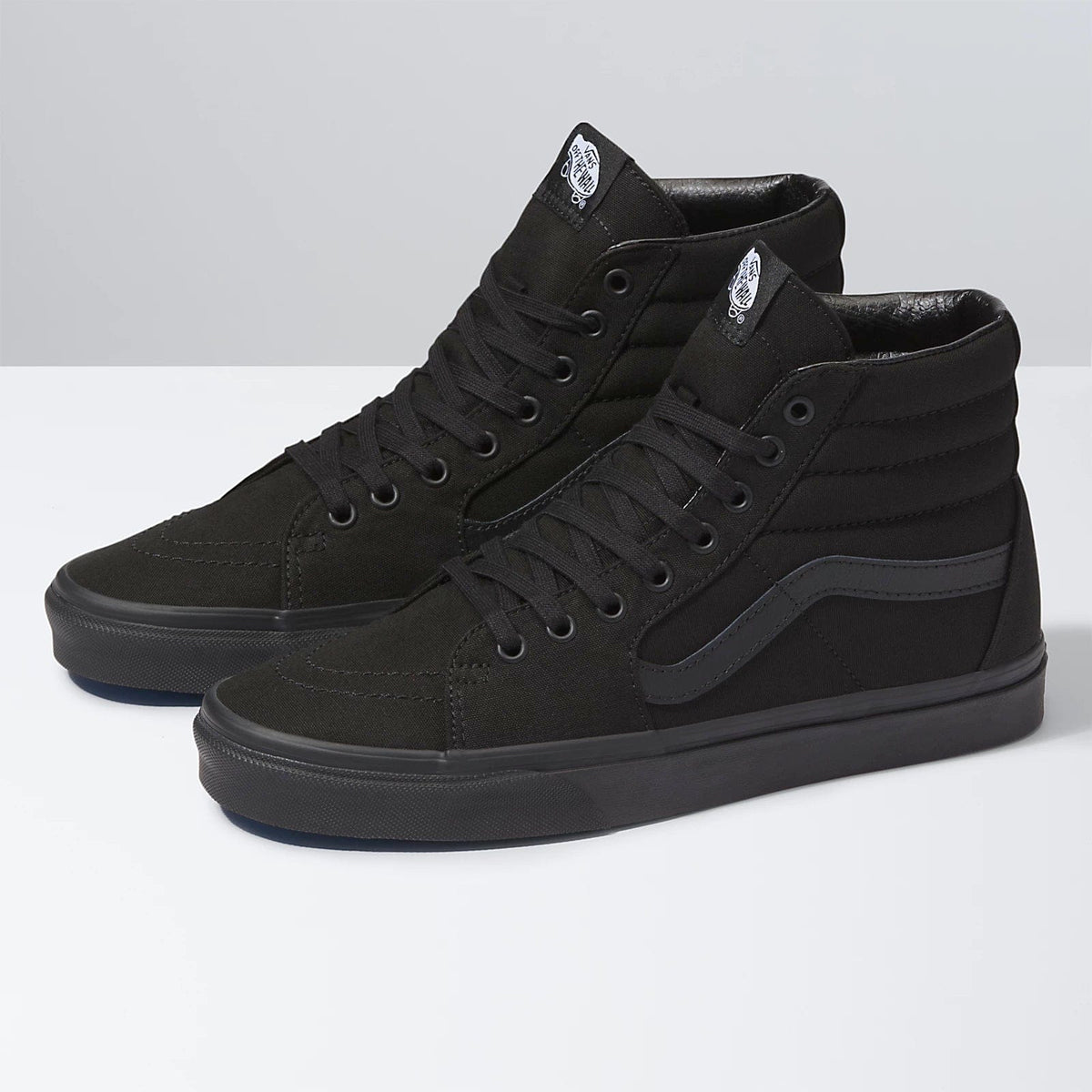 Vans Sk8-Hi sneakers in black with canvas upper, suede trim, padded collar, and side stripe detail, front-side view.