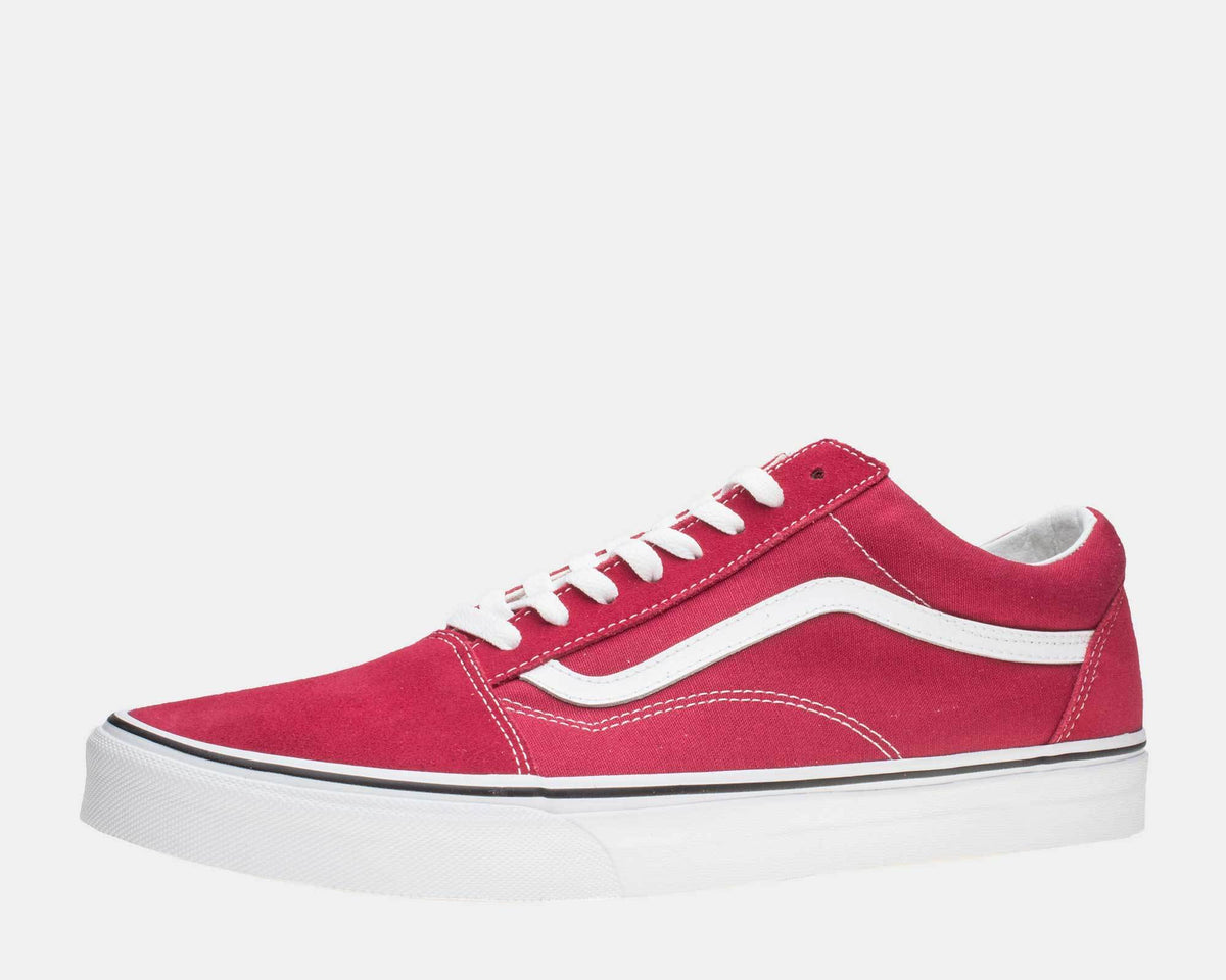 Vans Old Skool sneakers in red suede and canvas with white side stripe, lace-up closure, and white rubber sole, side view.
