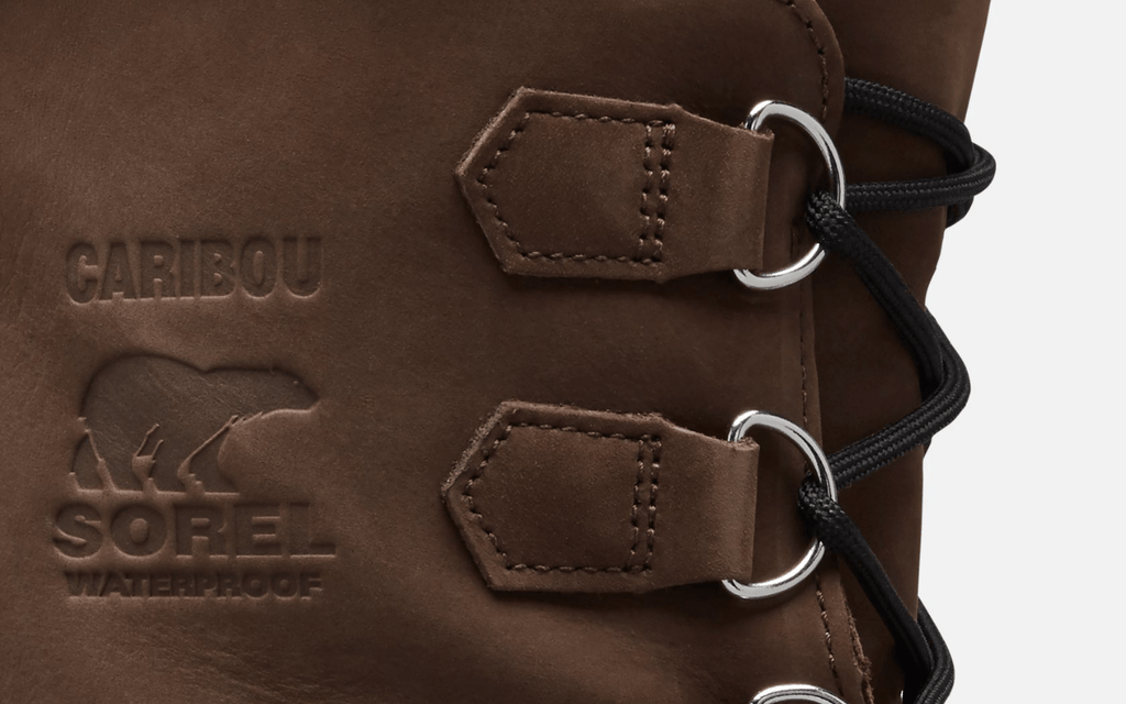 Sorel Caribou Winter Boots close-up of brown leather upper with embossed branding and waterproof detail, featuring durable metal eyelets and black laces.