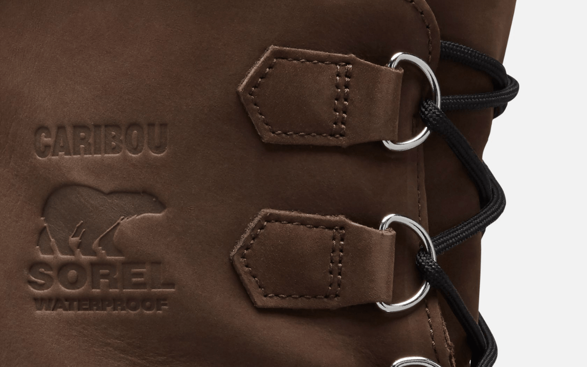 Sorel Caribou Winter Boots close-up of brown leather upper with embossed branding and waterproof detail, featuring durable metal eyelets and black laces.