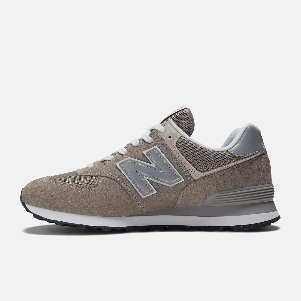 New Balance 574 Core sneakers in taupe suede with gray mesh panels and iconic "N" logo, side profile view.