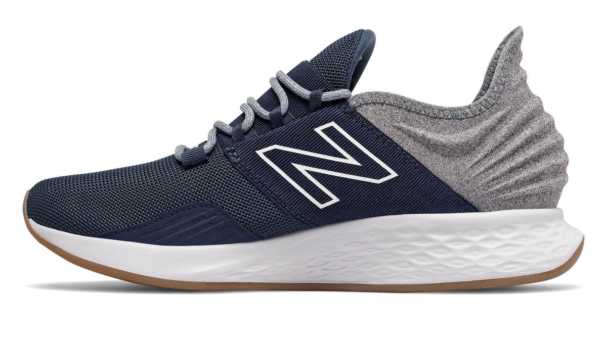 New Balance Fresh Foam Roav Tee Shirt running shoes side view in navy blue and gray with mesh upper, cushioned sole, and textured heel design.
